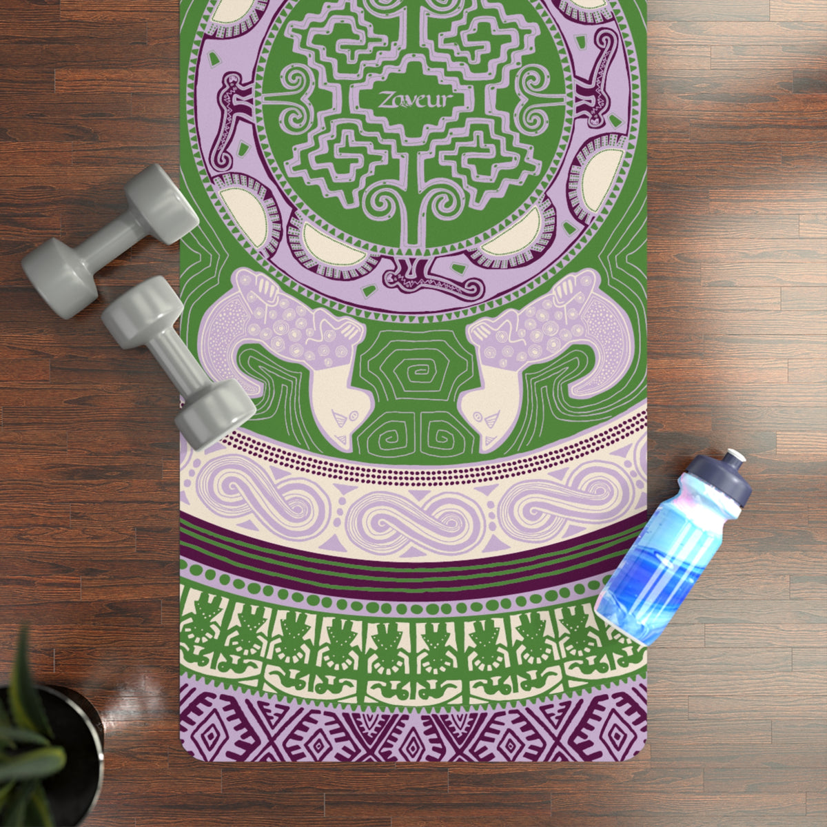 Colombian Dreams Mandala Cats yoga mat in green and lilac on a wood floor with dumbbells and a water bottle