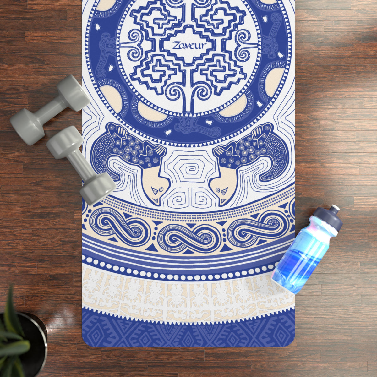 Top-down view of the Colombian Dreams blue mandala yoga mat on a wood floor with dumbbells and a water bottle