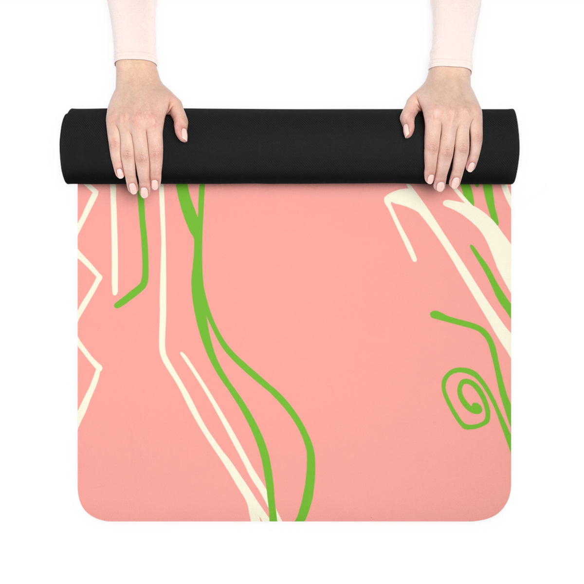 Hands unrolling a Queen of Phoenix pink yoga mat with green and cream flowing lines