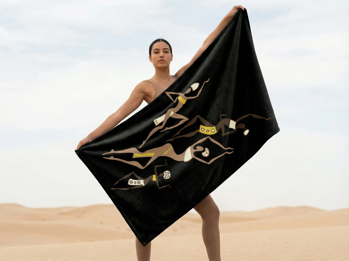 Woman holding the black Dancing Ladies blanket open in the desert, dancing figures in brown, gold and cream