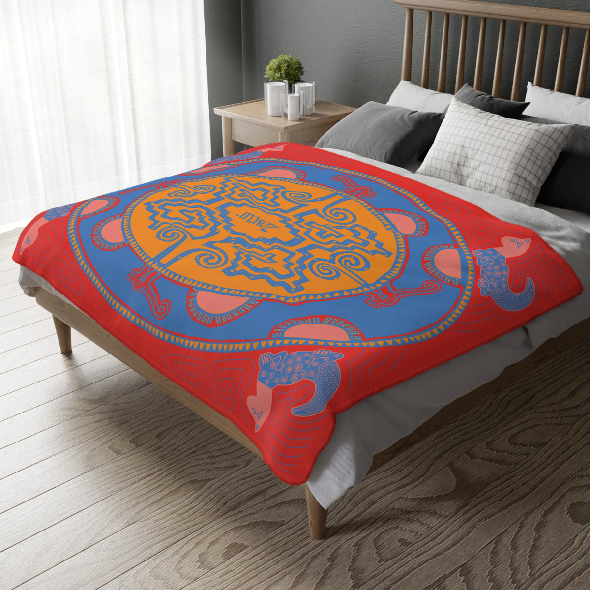 Colombian Dreams red, blue and orange medallion blanket draped over a bed by a window with sheer curtains