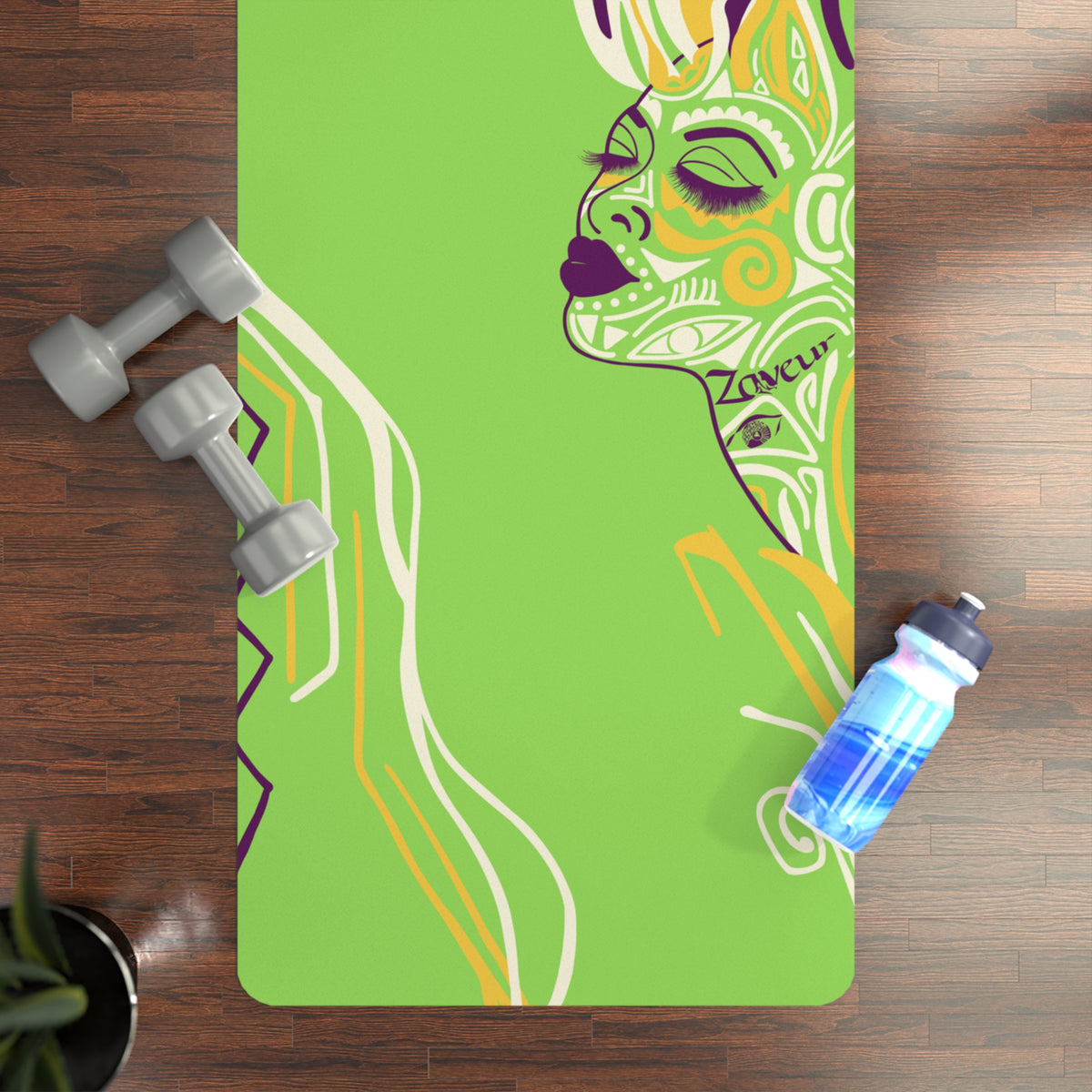 Queen of Phoenix lime green yoga mat with yellow and purple line-art face on a wood floor with dumbbells