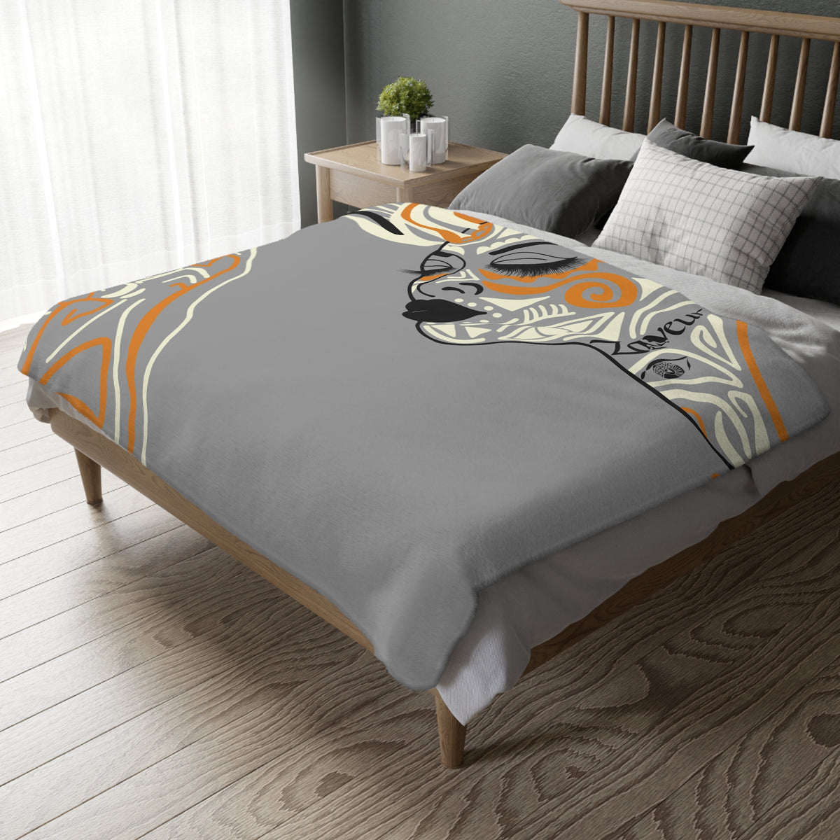 Queen of Phoenix gray blanket with an orange and cream illustrated portrait spread over a wooden bed
