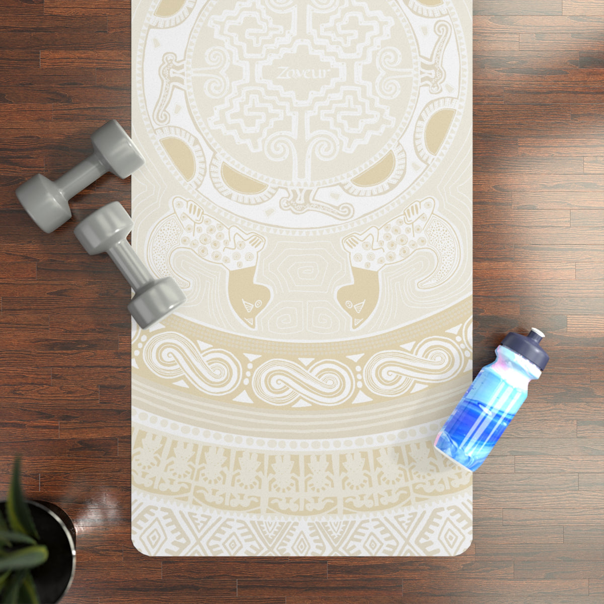 Top-down view of the Colombian Dreams beige mandala yoga mat on a wood floor with dumbbells and a water bottle