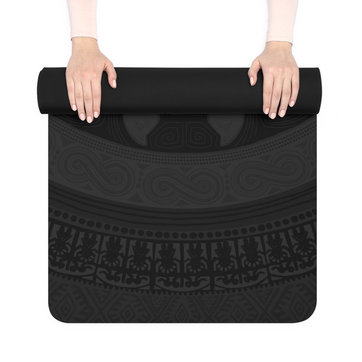 Hands unrolling the Colombian Dreams black mandala yoga mat, showing the dark geometric border