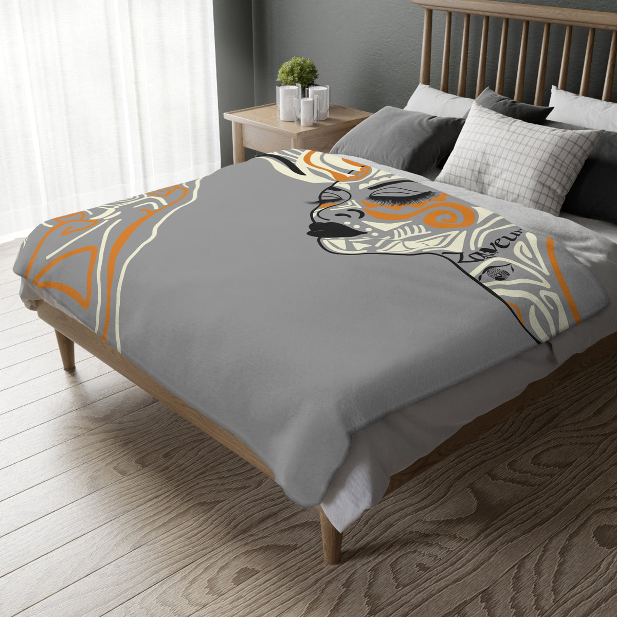 Queen of Phoenix gray microfiber blanket on a bed, closed-eye line-art face and orange geometric pattern at the edge