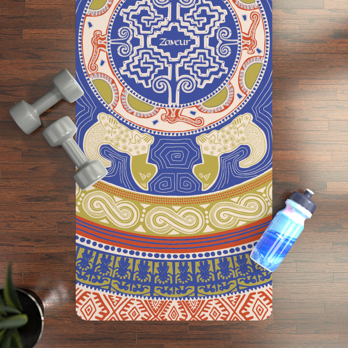 Colombian Dreams Mandala Circle yoga mat in blue and gold on a wood floor beside dumbbells and a water bottle