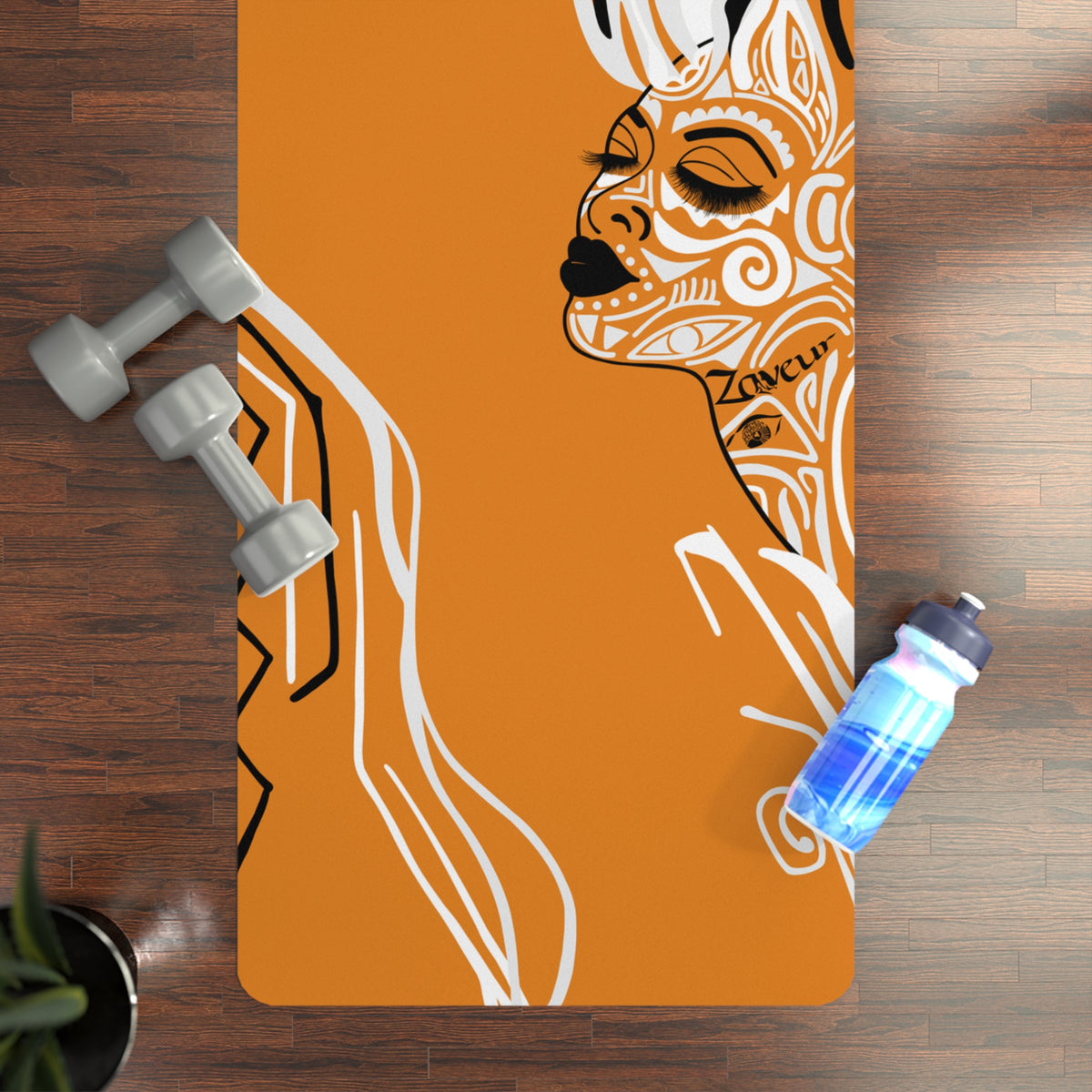 Queen of Phoenix orange yoga mat with white and black line-art face, shown from above with dumbbells and water bottle