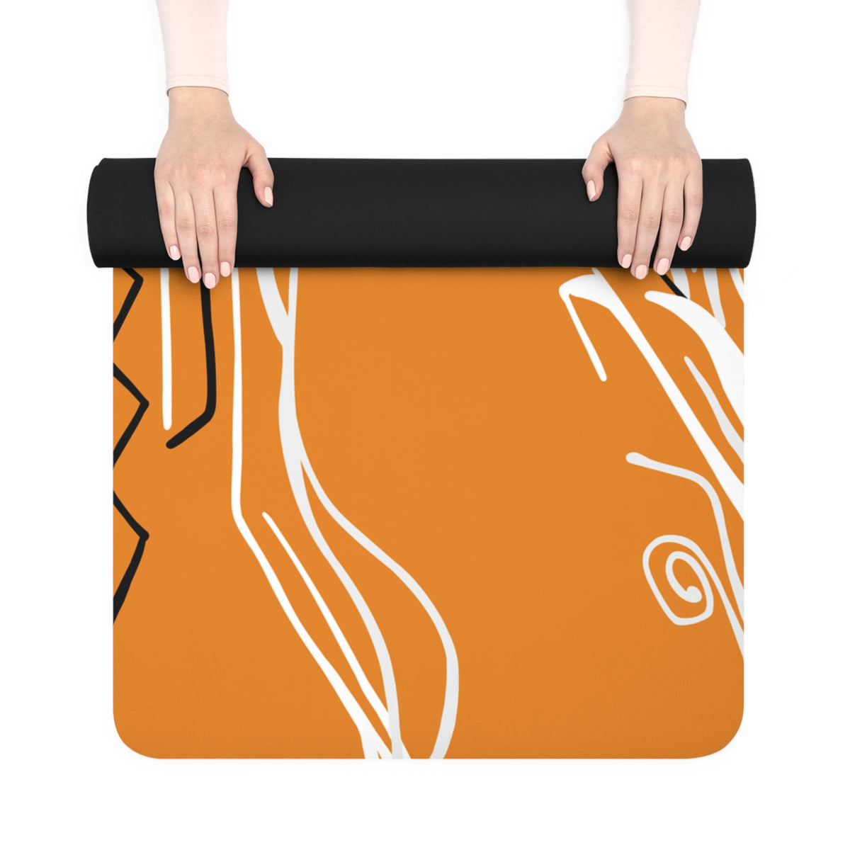 Hands unrolling a Queen of Phoenix orange yoga mat with white and black flowing lines