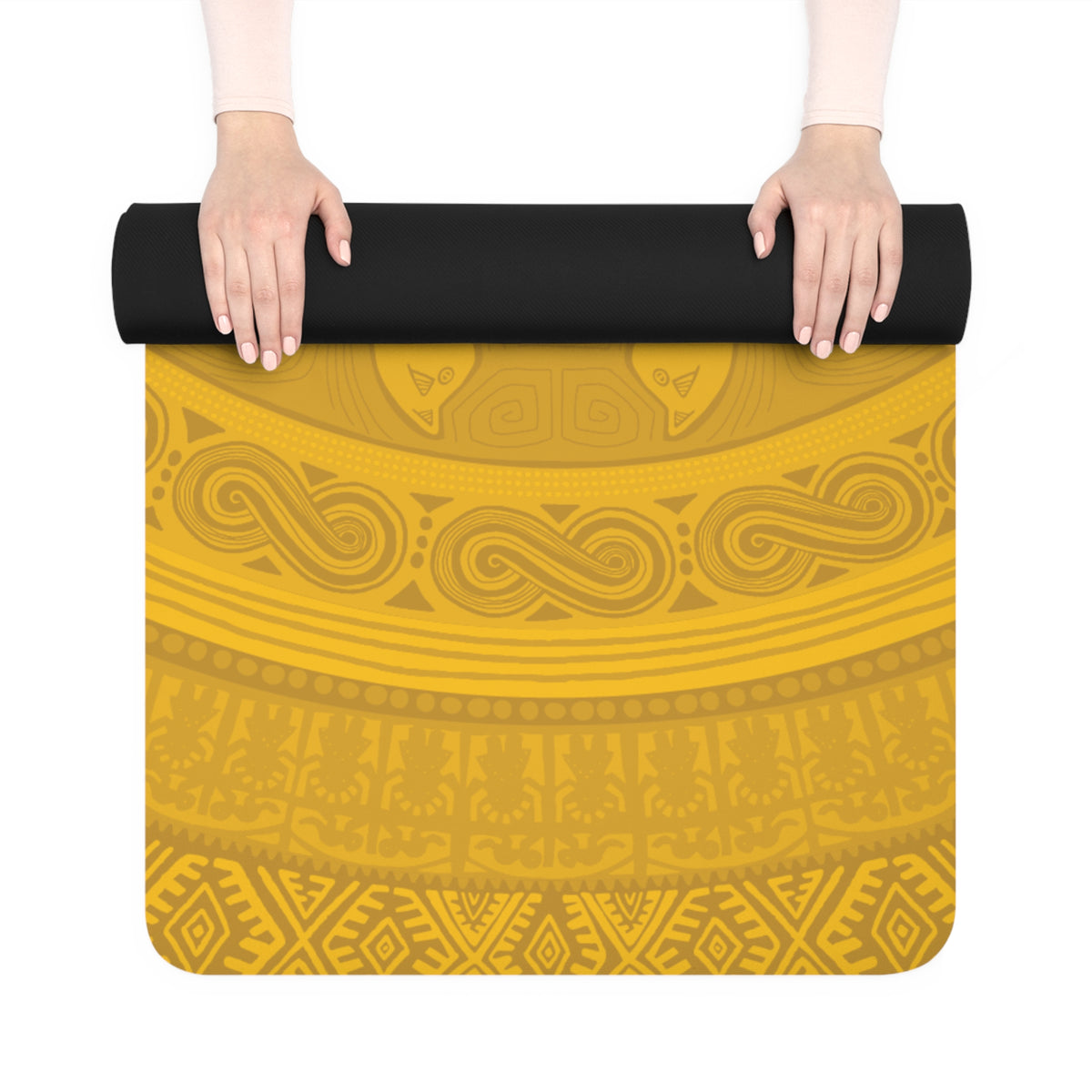 Hands unrolling the Colombian Dreams golden mandala yoga mat, showing gold geometric bands below the black rolled end