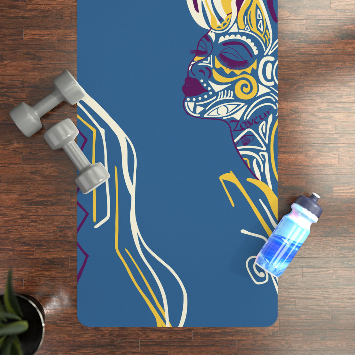 Queen of Phoenix blue yoga mat with patterned line-art face on a wood floor, dumbbells and water bottle nearby