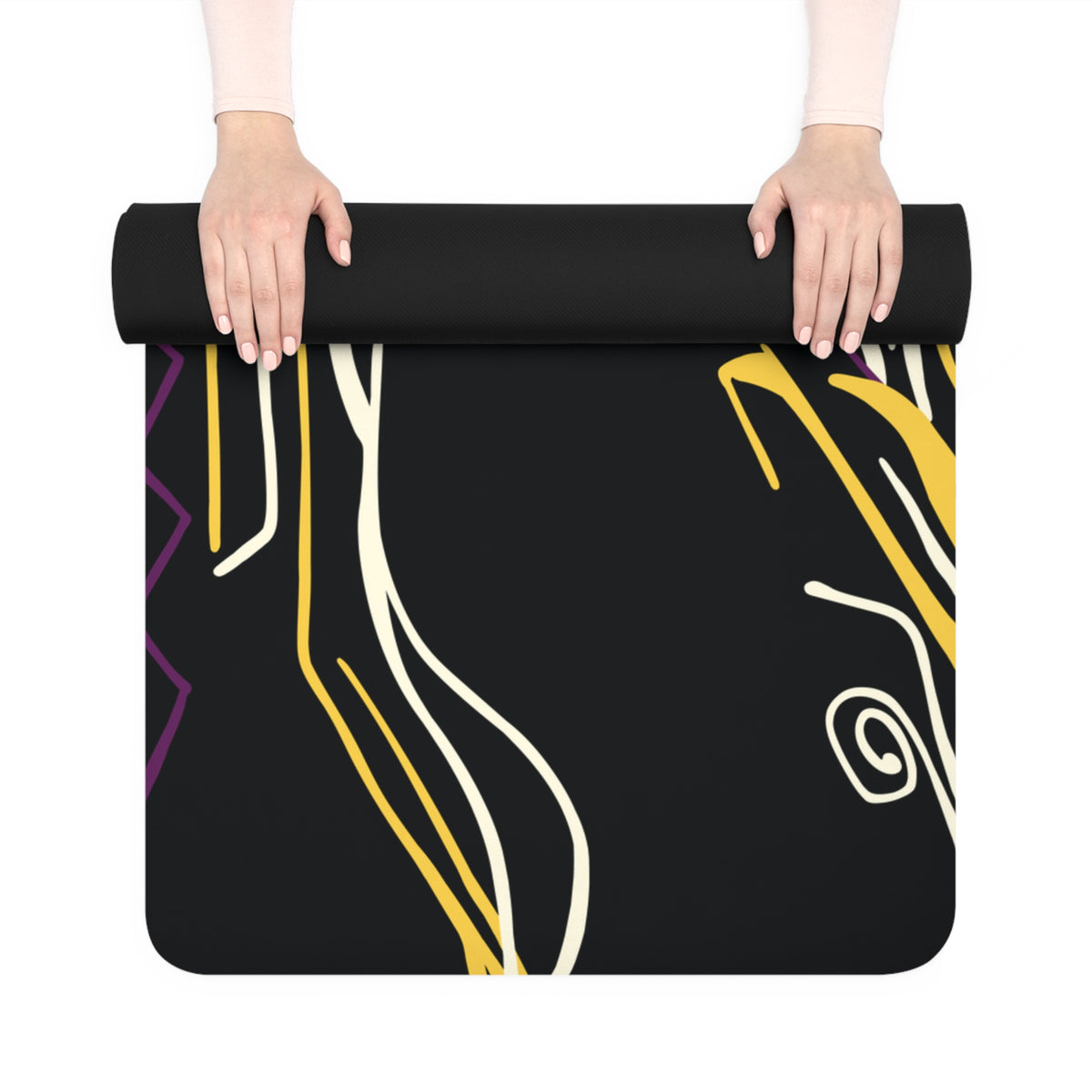 Hands unrolling a Queen of Phoenix black yoga mat with yellow, cream and purple flowing lines