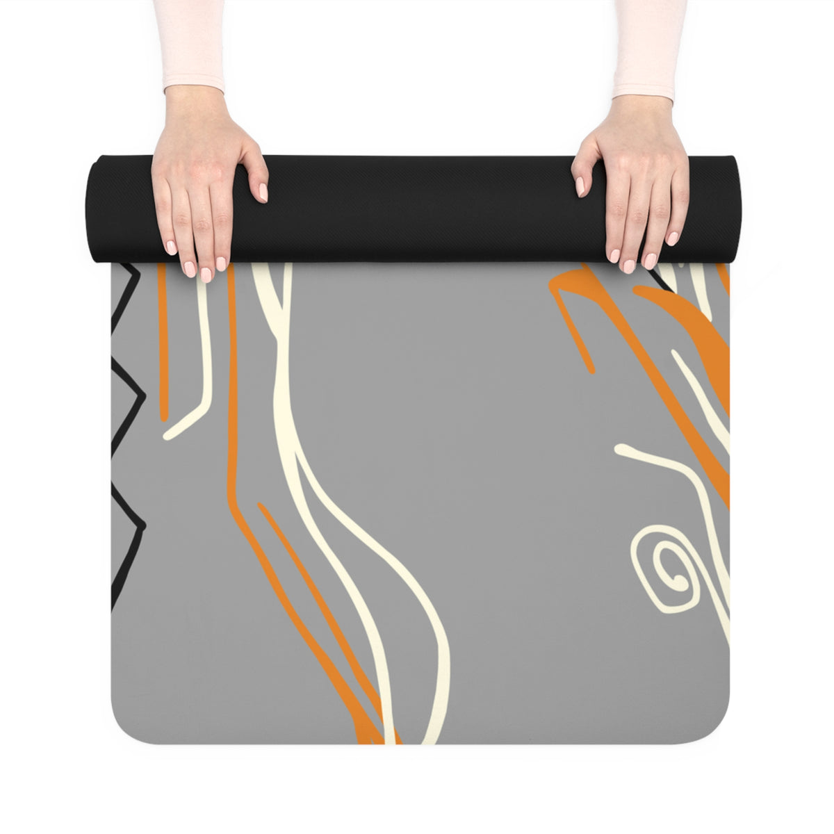 Hands unrolling the grey Queen of Phoenix rubber yoga mat, showing orange and cream line art and black underside