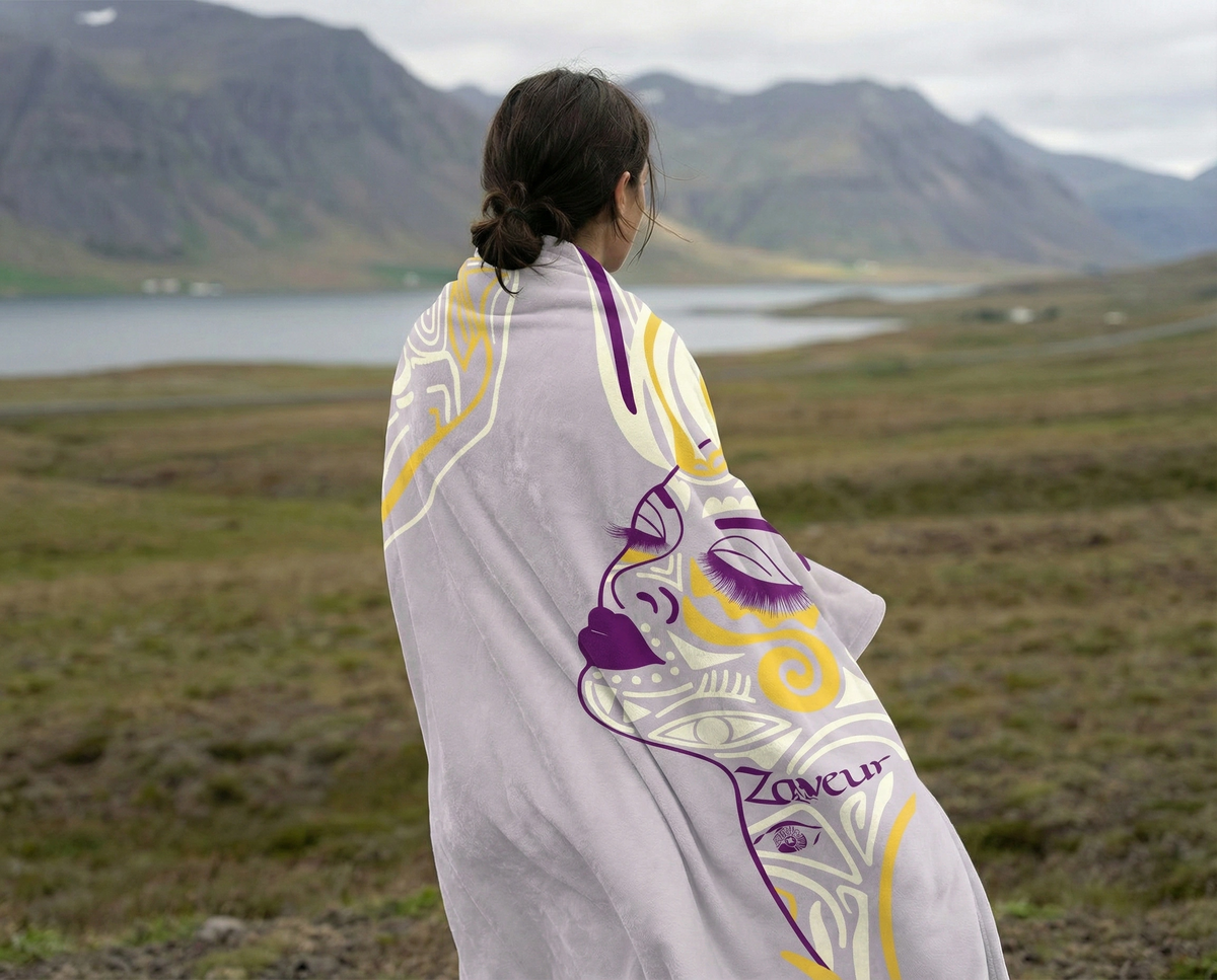 Woman seen from behind wrapped in the lavender Queen of Phoenix blanket, purple line-art face, lake and hills