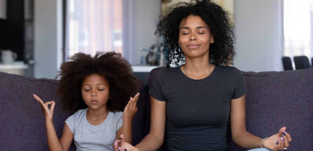 Mother and daughter meditating together indoors