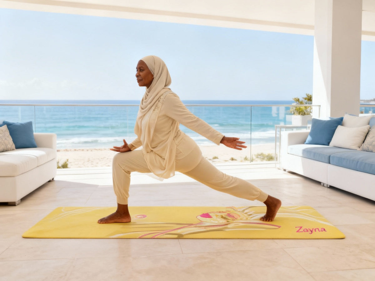 Senior woman practicing a yoga lunge on a yellow yoga mat by the ocean at sunset.